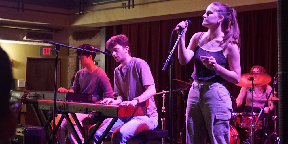 Students singing in a band. Two are behind pianos.